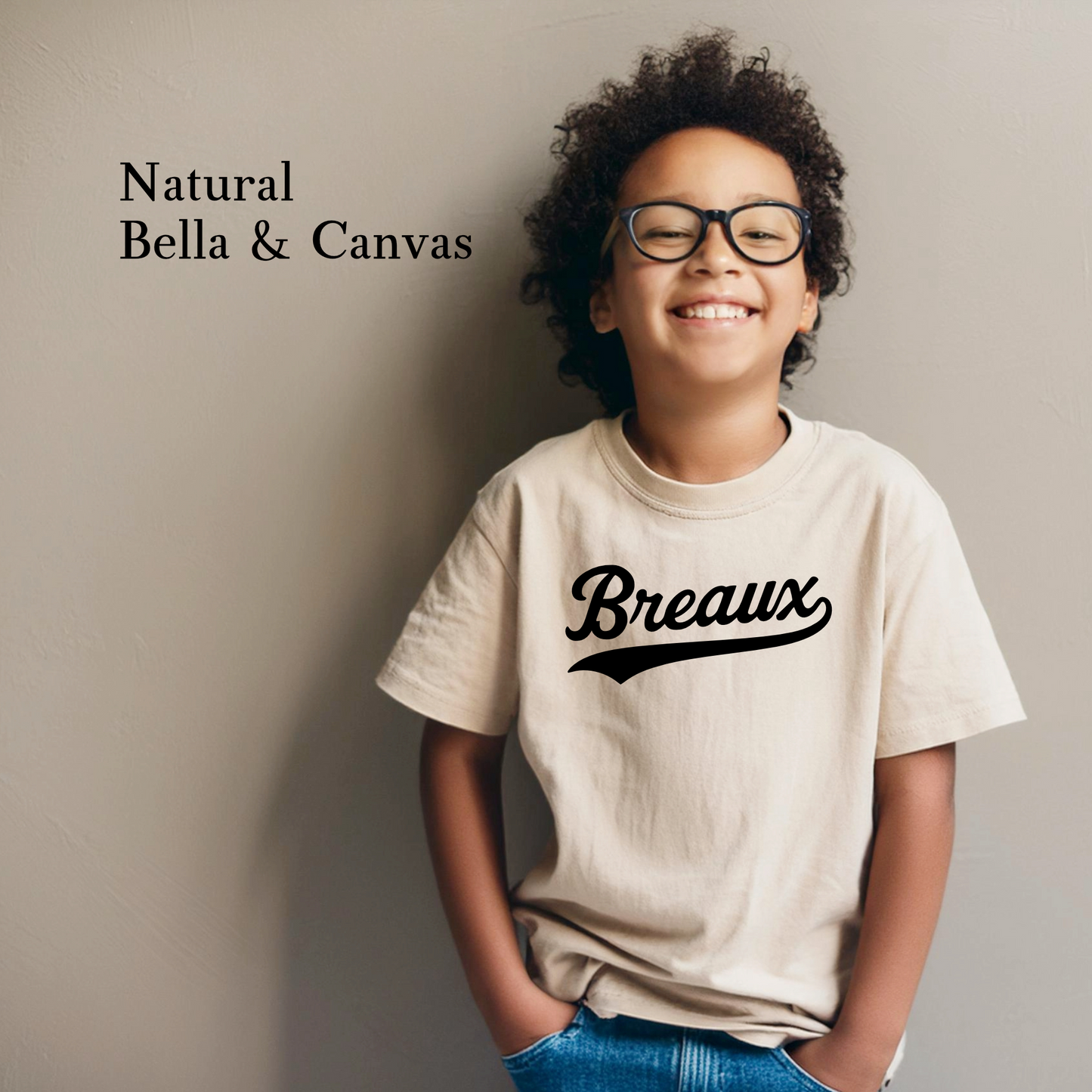 Smiling child wearing Breaux youth T-shirt in bold varsity-style script