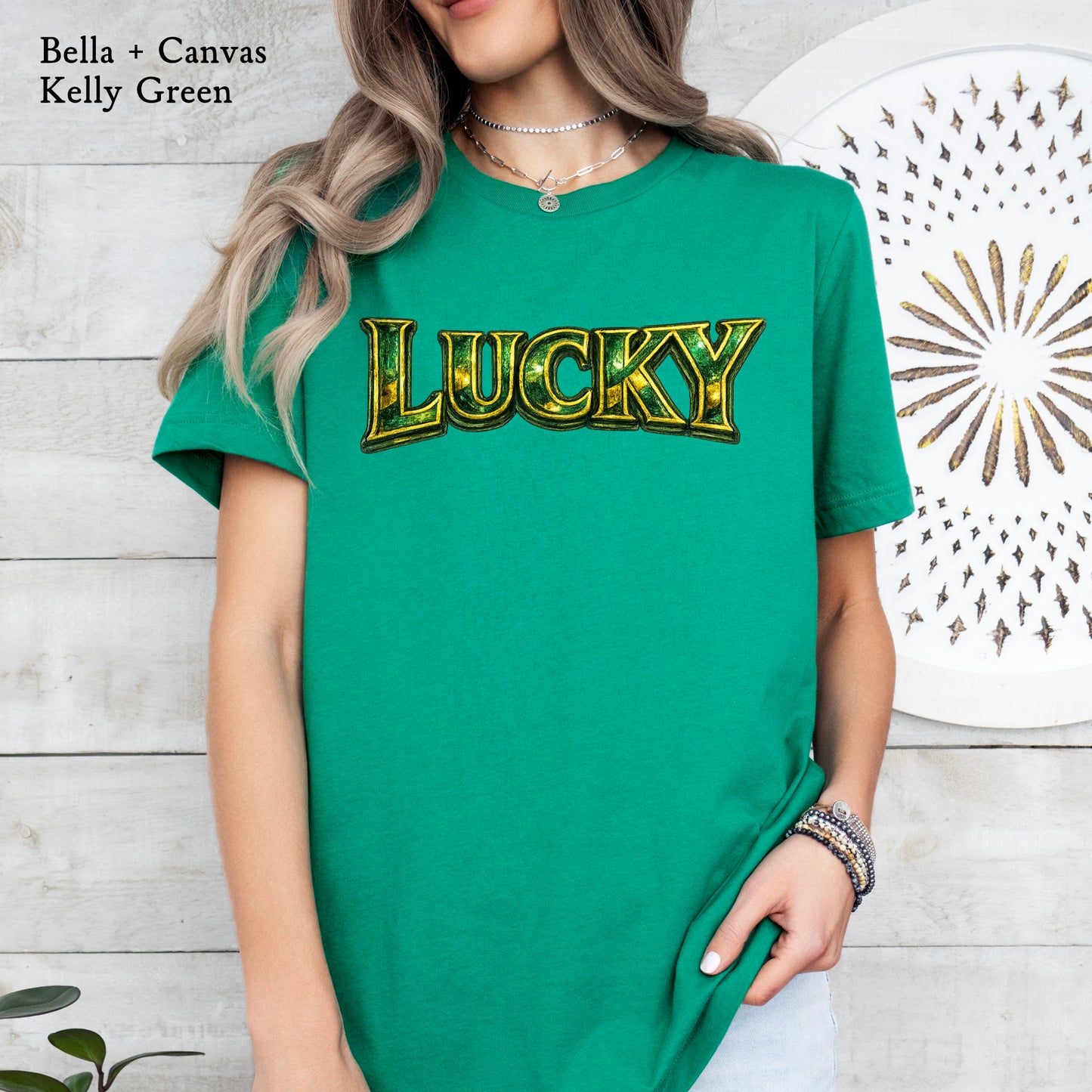Person wearing a green t-shirt with 'LUCKY' printed in gold, against a light wooden panel background.