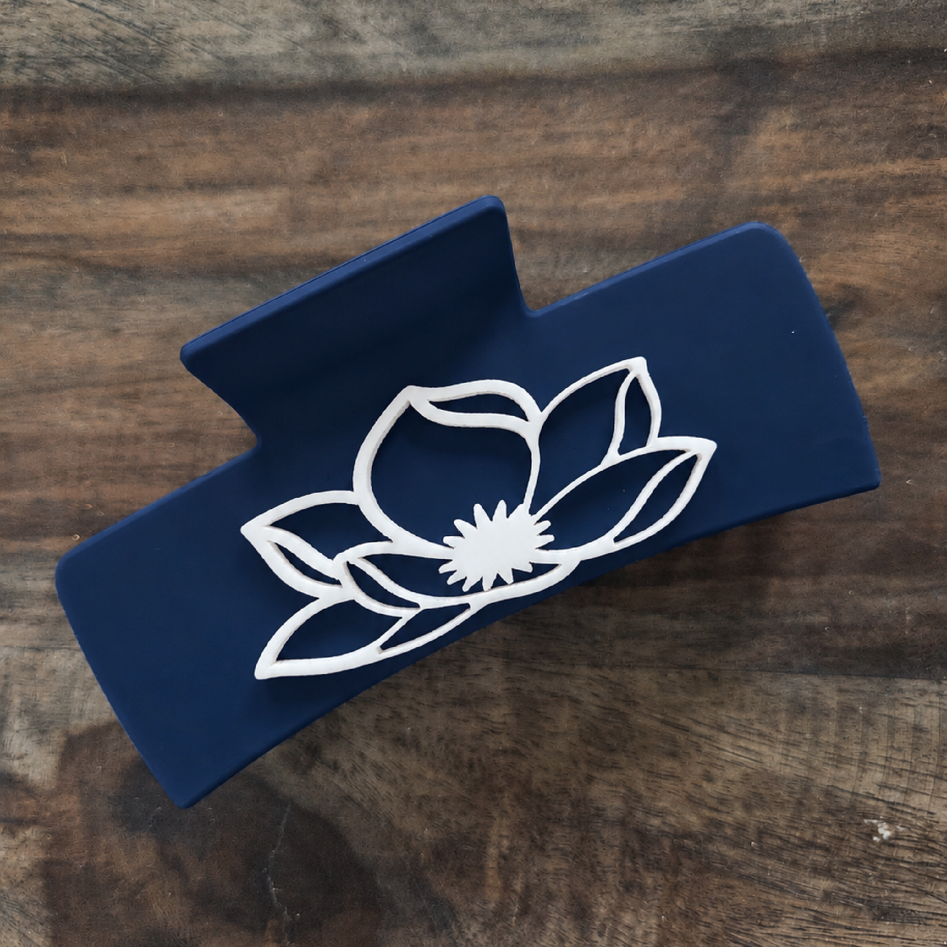 Navy acrylic hair claw clip featuring a white magnolia flower design on both sides.
